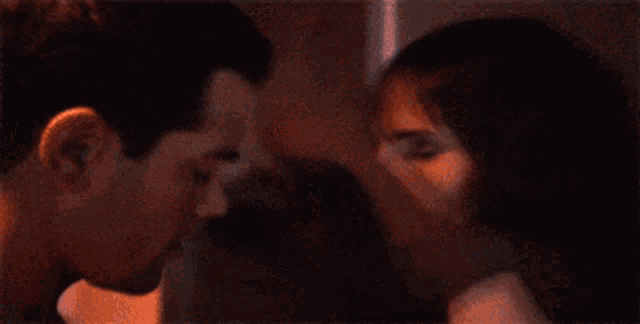 a man and woman are kissing each other in a dark room .