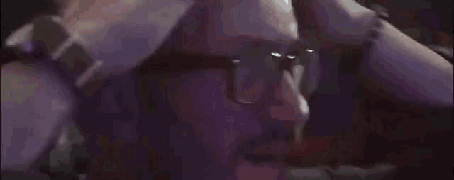 a close up of a person 's face with a purple background and a bracelet on their wrist .