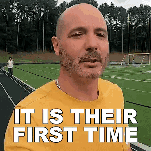 a bald man with a beard wearing a yellow shirt that says " it is their first time "