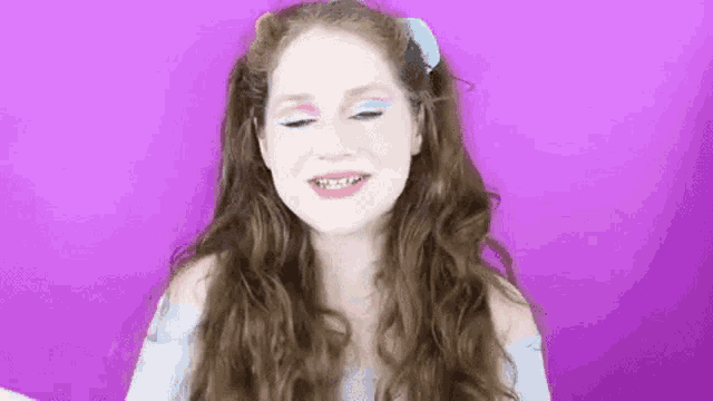 a woman with long hair and braces on her teeth is smiling .