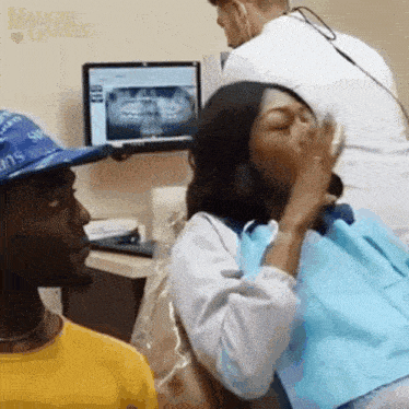 a man in a blue hat is looking at a woman in a dental chair