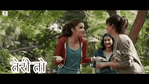 a group of women are standing next to each other in a forest and talking .