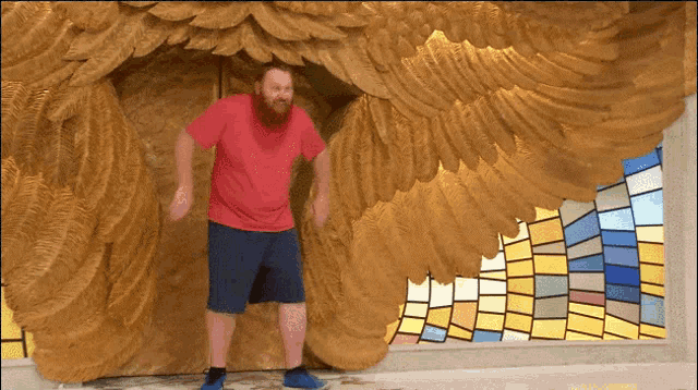 a man in a red shirt is standing in front of a large sculpture