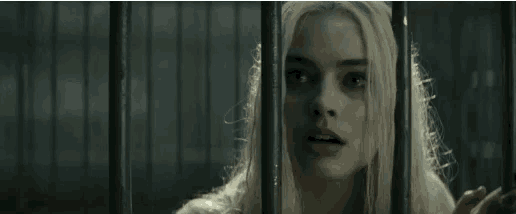 a woman with blonde hair is behind bars in a cage and looking at the camera .