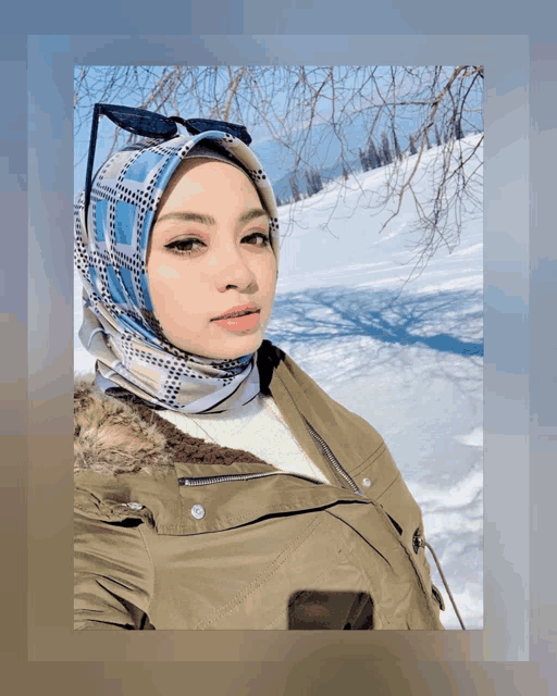 a woman wearing a hijab stands in the snow