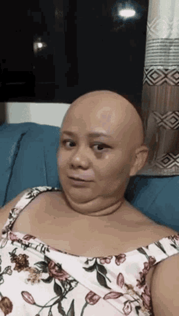 a woman with a bald head is sitting on a blue couch .