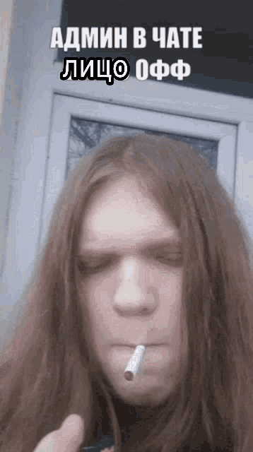 a man with long hair is smoking a cigarette with a caption in russian