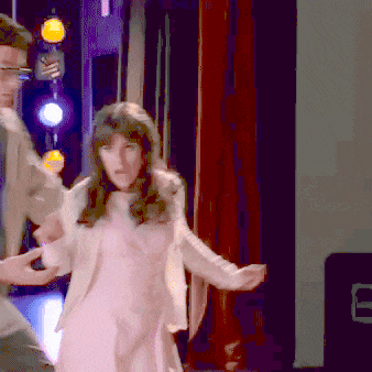 a man and a woman are dancing in front of a red curtain