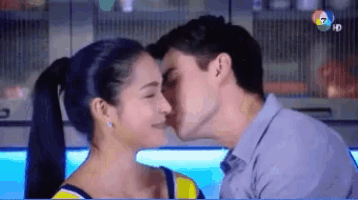 a man and a woman are kissing in a kitchen and the man is kissing the woman 's forehead