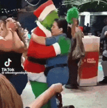 a grinch costume is hugging a woman in a police uniform .