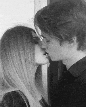 a man and a woman are kissing in front of a wall