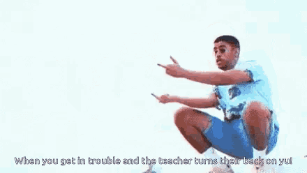 a man is squatting down and giving the middle finger while looking at his phone .