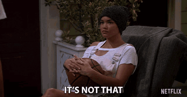 a woman sitting on a couch holding a basketball with the words " it 's not that " next to her