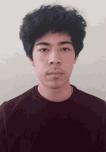 a young man with a beard wearing a maroon shirt