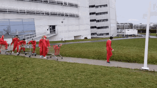 a group of people in red jumpsuits push shopping carts down a sidewalk