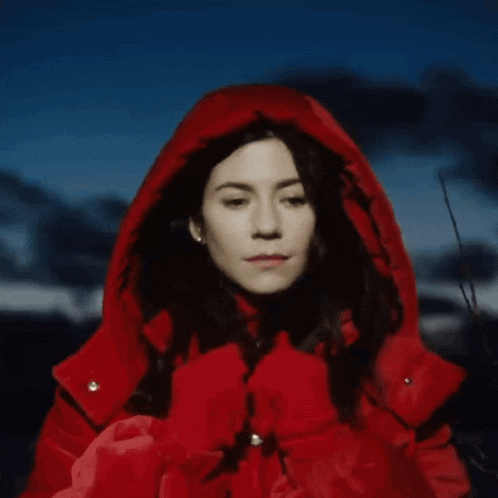 a woman wearing a red hooded jacket looks down