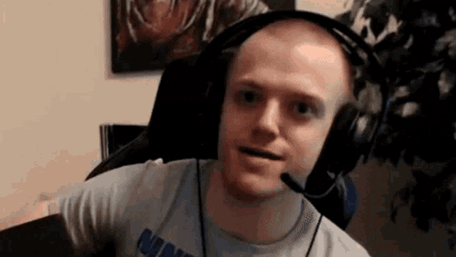 a man wearing headphones and a microphone is sitting in a chair and making a funny face .