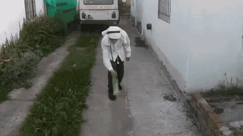 a man is walking down a sidewalk holding a green bag .