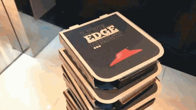 a stack of pizza boxes that say live edge crust on them