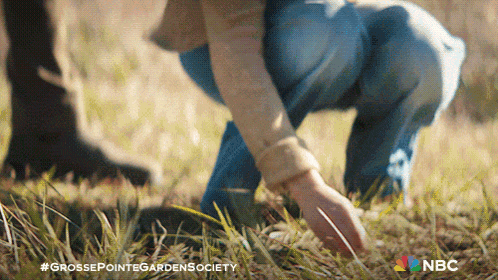a person is kneeling down in the grass with a nbc logo in the background