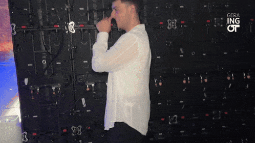 a man in a white shirt is standing in front of a wall that says gira ing of