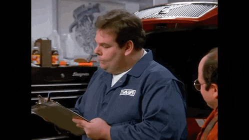 a man wearing a blue shirt that says saab is looking at a clipboard
