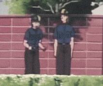 two police officers standing next to each other in front of a brick wall .