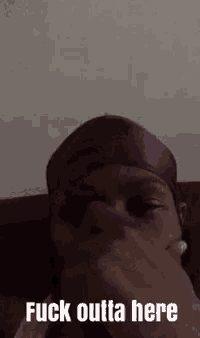 a man wearing a purple headband is sitting on a couch and covering his mouth .