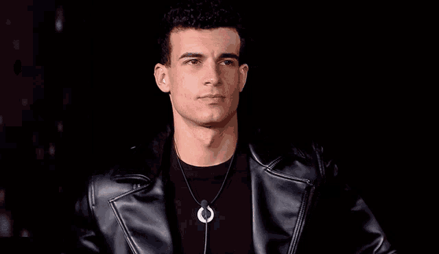a young man wearing a leather jacket and a necklace .