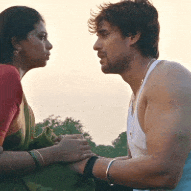 a man and a woman are looking at each other and holding hands