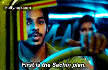 a man is driving a car with the words `` first is the sachin plan '' written on the screen .