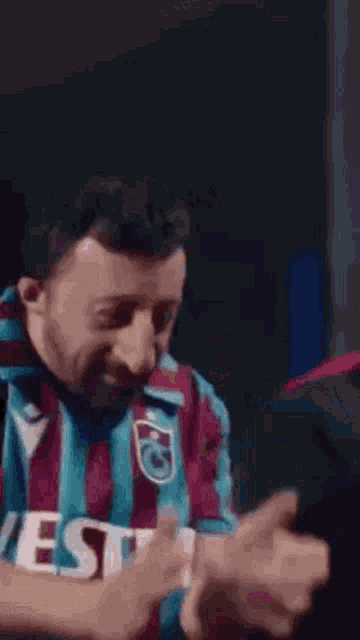 a man wearing a striped shirt with the word veste on it is making a face .