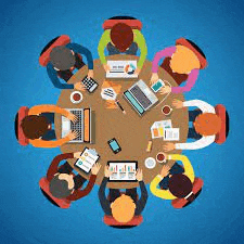 a group of people are sitting around a round table with laptops .