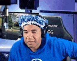 a man wearing a blue hoodie and a blue hat is sitting in a chair .