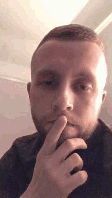 a man with a beard is touching his nose with his finger