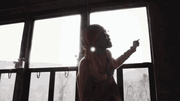a person is standing in front of a window and pointing at something