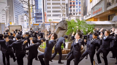 a group of men in suits are dancing in front of a sign that says ' aoi ' on it