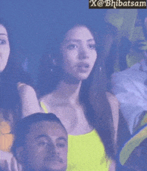 a woman in a yellow tank top is sitting in a stadium with a man .