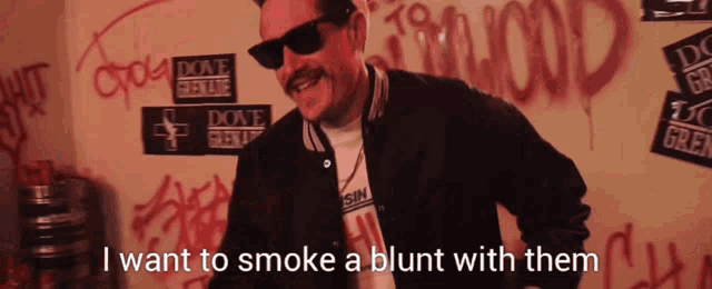 a man wearing sunglasses says " i want to smoke a blunt with them " in front of graffiti on the wall