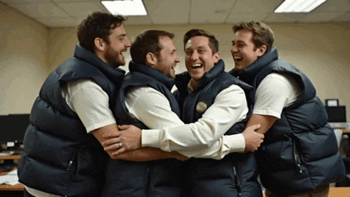 a group of men wearing vests hugging each other and laughing