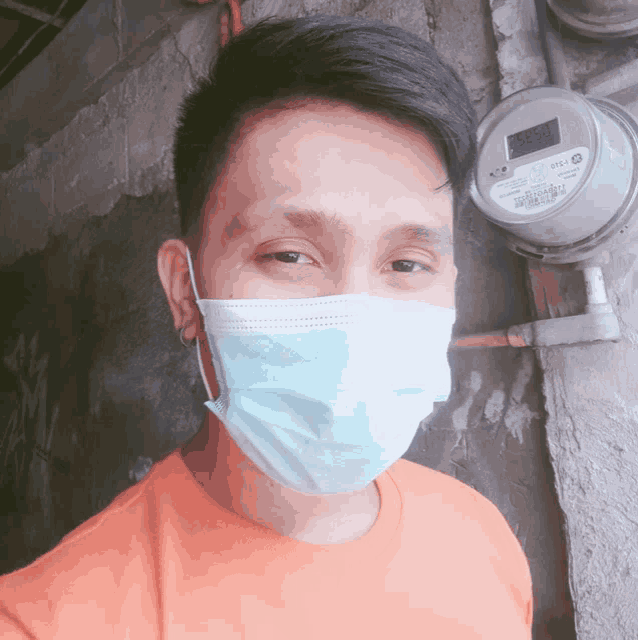 a man wearing a face mask is standing in front of a meter that says ' eec ' on it