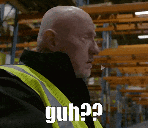 a bald man in a yellow vest says guh