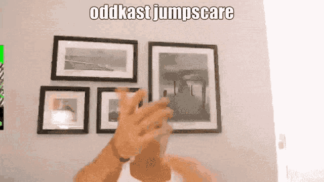 a man applauds in front of a wall of framed pictures with the words oddkast jumpscare above him