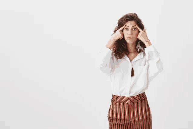 a woman wearing striped pants and a white shirt holds her hands to her forehead