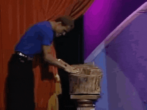 a man in a blue shirt is standing next to a statue on a stage