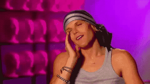 a man wearing a headband and a tank top has his eyes closed and his hand on his face .