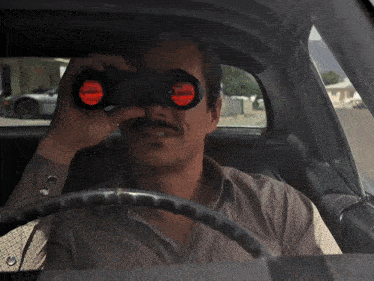 a man looking through binoculars in a car