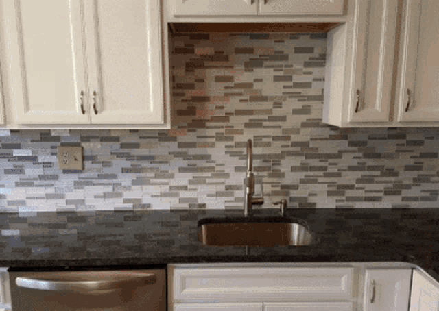 a kitchen with white cabinets and a black counter top