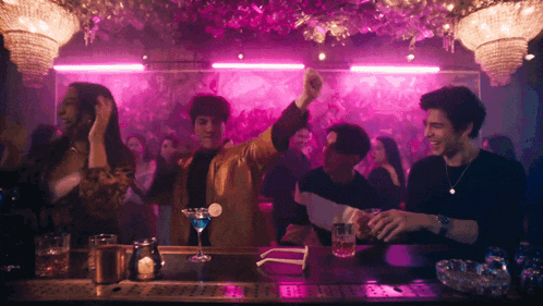a group of people are dancing at a bar with a martini in the middle