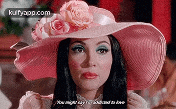 a woman wearing a pink hat with roses on it is talking to someone .